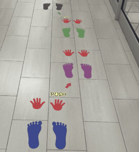 Colorful sensory path with hand and foot prints for children in a hallway.